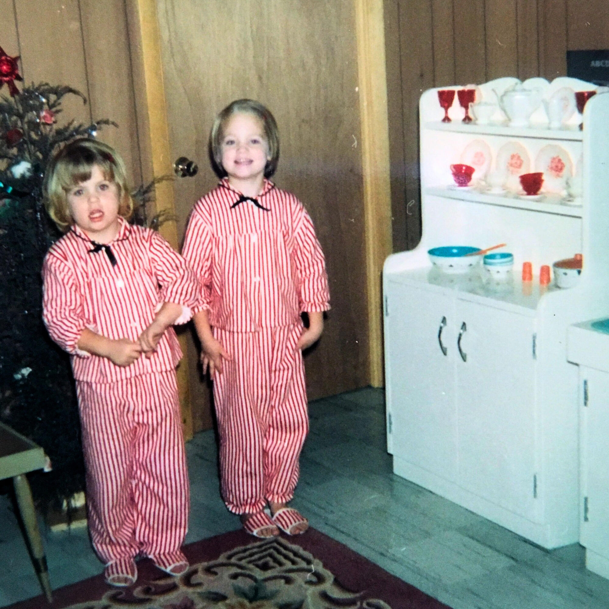 Annie and Eileen Christmas Eileen and Annie as children, wearing matching striped pajamas at Christmas beside hutch made by Santa